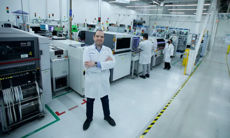 Markham Veoneer - Man in white smock with crossed arms in front of machines